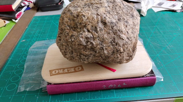 The book beneath a wooden board and a rock. The book beneath a wooden board and a rock.
