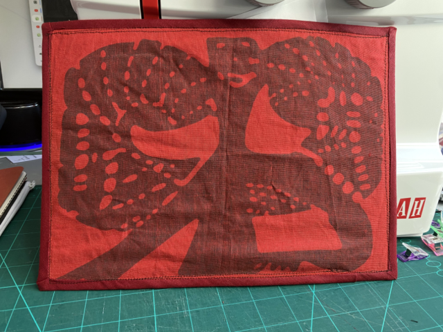 The sewn TN cover rests against the sewing machine, the monstrous logo fills the whole front. The sewn TN cover rests against the sewing machine, the monstrous logo fills the whole front.