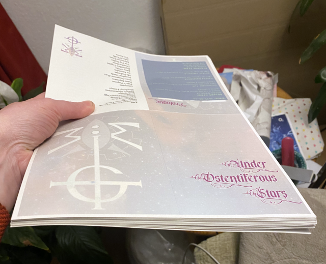 Someone is holding a batch of papers (40 sheets) that have been printed on. On the bottom right quarter of the top page the combined logos of the bands Ghost and The Mechanisms are seen. On the red bottom quarter the words "Under Ostentiferous Stars" are printed. Someone is holding a batch of papers (40 sheets) that have been printed on. On the bottom right quarter of the top page the combined logos of the bands Ghost and The Mechanisms are seen. On the red bottom quarter the words "Under Ostentiferous Stars" are printed.