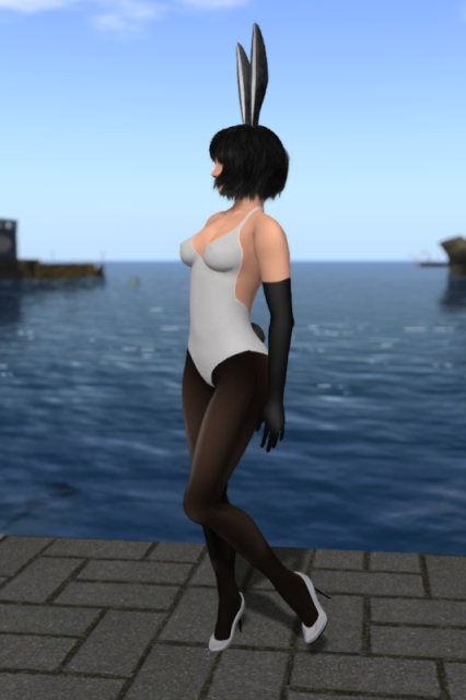 Posing in a sort of "negative bunny" outfit with the same white and black bunny ears, the same black bunny tail, the same black gloves and the same make-up as in the previous outfit, now combined with a white bathing-suit, dark black seamed sheer tights and white pumps